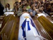 FILE - In this Friday, May 26, 2017 file photo, relatives of Coptic Christians who were killed during a bus attack, surround their coffins, during their funeral service, at Abu Garnous Cathedral in Minya, Egypt. The Libya connection in the Manchester concert bombing and FridayÇƒÙs attack on Christians in Egypt has shone a light on the threat posed by militant Islamic groups that have taken advantage of lawlessness in the troubled North African nation to put down roots, recruit fighters and export jihadists to cause death and carnage elsewhere.