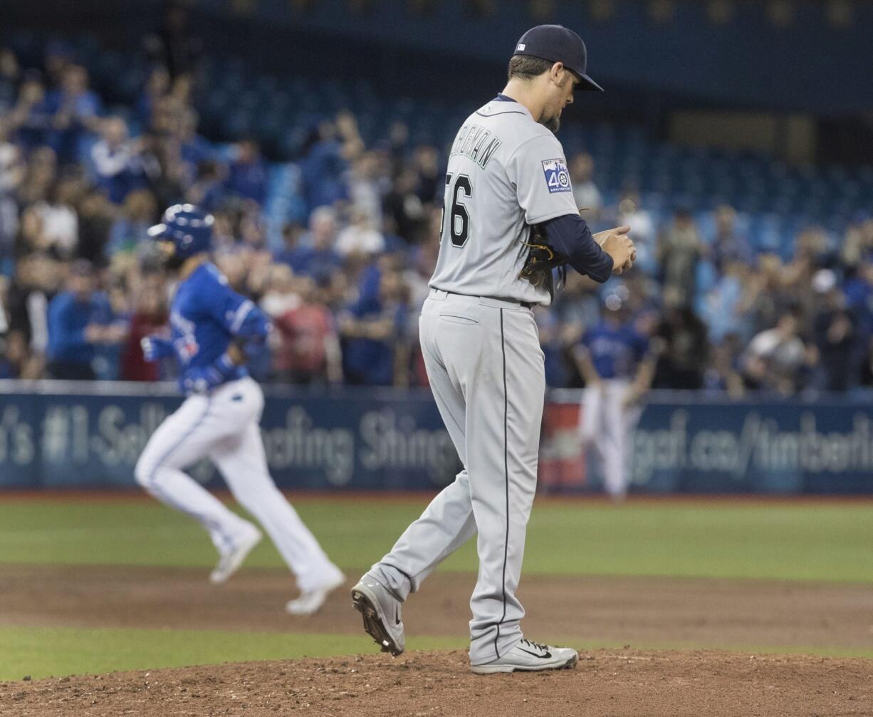 Seattle Mariners starting pitcher Christian Bergman walks back up the mound after giving up a two-run home run to Toronto Blue Jays' Jose Bautista, rounding the bases at left, during the third inning of a baseball game in Toronto on Friday May 12, 2017.