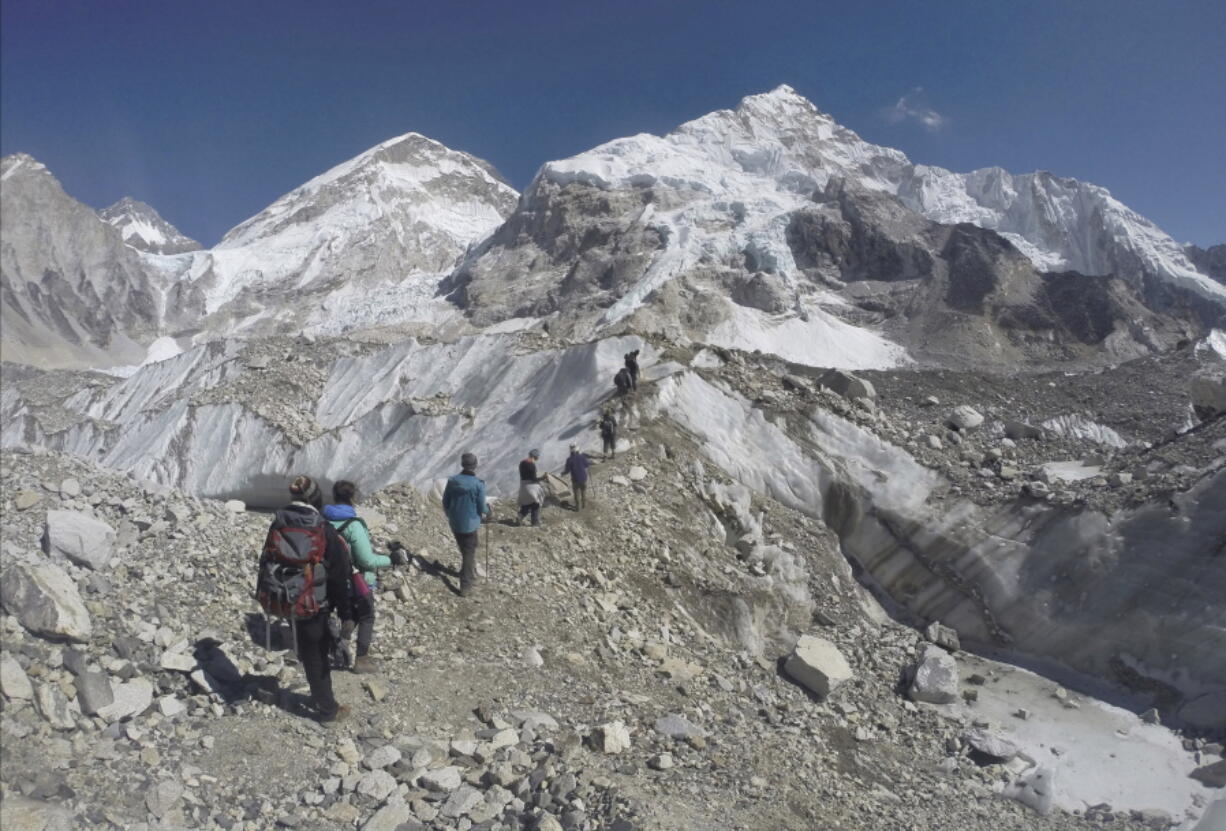 International trekkers pass through a glacier at the Mount Everest base camp, Nepal on Feb. 22, 2016. A Nepalese official says Sherpa workers are fixing the final route to the summit of Mount Everest and the first climb of the season could be days away.