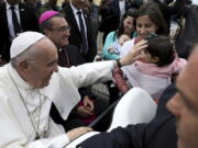 Pope Francis greets a child as he arrives at the Monte Real Air Base in Leiria, Portugal, Friday, May 12, 2017. Pope Francis will canonize on Saturday in Fatima two poor, illiterate shepherd children whose visions of the Virgin Mary 100 years ago marked one of the most important events of the 20th-century Catholic Church.