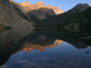 Pika Peak, shown at sunset on Aug. 31, 2016, photo, is mirrored in Echo Lake, one of scores that dot Montana's Absaroka-Beartooth Wilderness, making the region popular for hikers and anglers alike.