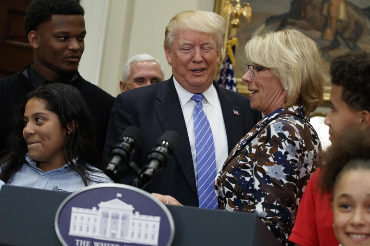 President Donald Trump stands with Education Secretary Betsy DeVos as he arrives to speak during a school choice event in the Roosevelt Room of the White House in Washington, Wednesday, May 3, 2017.