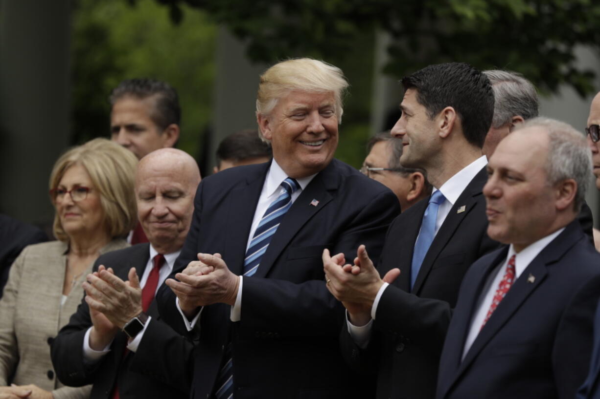 President Donald Trump, flanked by House Ways and Means Committee Chairman Rep. Kevin Brady, R-Texas, and House Speaker Paul Ryan of Wis., applaud in the Rose Garden of the White House on Thursday after the House pushed through a health care bill.