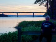 A Portland firefighter looks at the scene where a boat crashed into a pier of the Glenn Jackson Bridge Monday. A woman was killed and a man was injured.