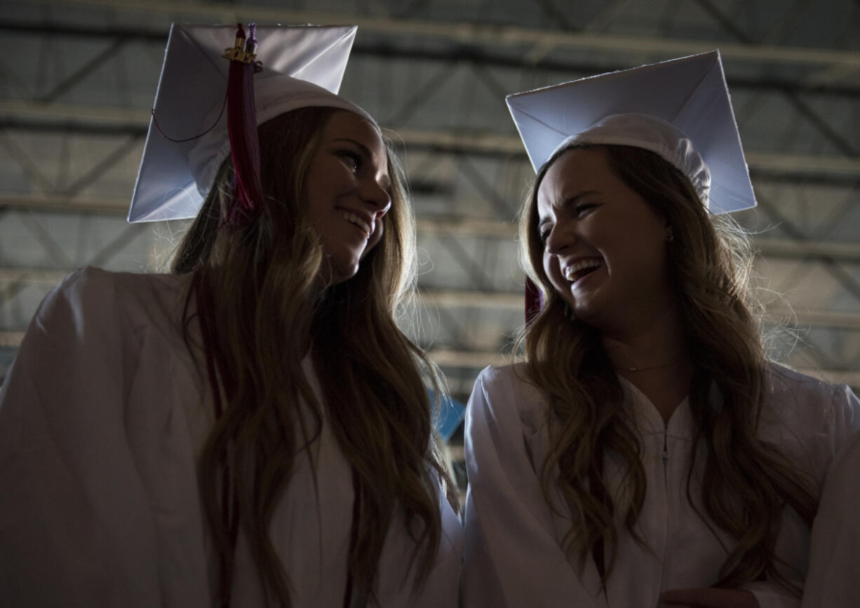 Breezy Hockett of Toutle, left, and Hailey Kimbrough of Longview chat as they wait for the Clark College commencement ceremony to begin Thursday evening at Sunlight Supply Amphitheater in Ridgefield.