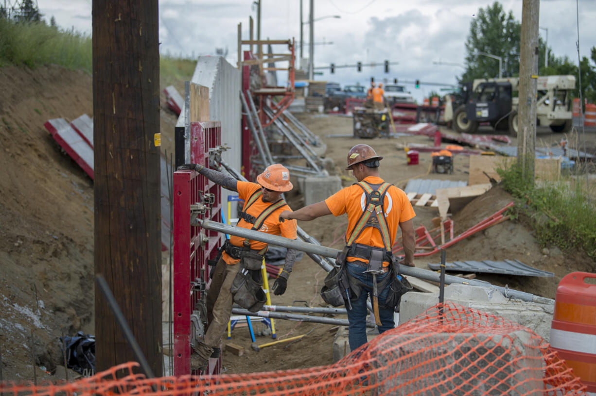 Tapani Inc.’s Genaro Leal, left, and Faron Kangas tackle a road improvement project along Northeast 18th Street on Tuesday morning. Construction companies say they are facing a labor shortage.