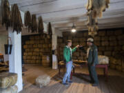 Mikah Meyer, left, 31, who is on a three-year road trip to visit all 417 national parks, and Ranger Bob Cromwell stop in the reconstructed fur store during Friday’s tour of Fort Vancouver National Historic Site.