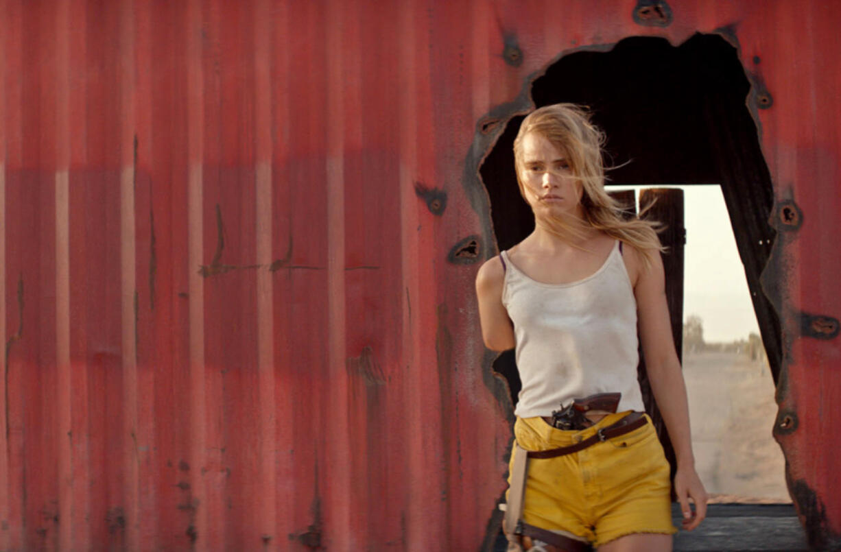 Arlen (Suki Waterhouse) walks among boxcars in “The Bad Batch.” Neon