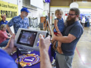 Andy Pyle, right, holds his daughter, Georgia, 2, as her vision is tested by a Salmon Creek Lions Club member Friday at Truman Elementary School in Vancouver.