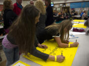 Jemtegaard Middle School sixth-graders Sophia Young, left, and Lily Barrett, sign their names on commemoration posters during the school district’s One Last Time celebration to say goodbye to the school building, which opened in 1981 and will be demolished this summer.