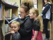 Jahara Craber, center, looks at a book with her daughter, Alleyah Sansburn, 4, while her 18-month-old son Liam Sansburn listens nearby May 30 at the Yacolt Library Express.