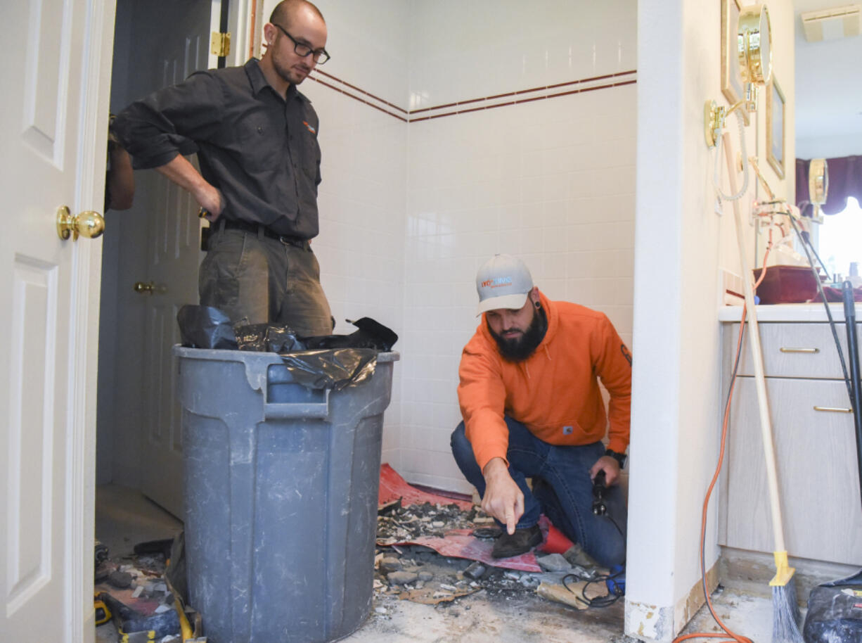 Daniel Culley, right, co-owner of Drytime Restoration, works Thursday with technician Isaac Liss on demolishing a shower that caused water damage to a home in Washougal.