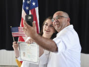 Heylen Medina, 25, poses for a photo holding her certificate of naturalization with her father, Lazaro Medina, following a naturalization ceremony for new American citizens at Pearson Air Museum on Friday. Lazaro left Cuba on a raft, gaining citizenship in the United States in 2005. His daughter, Heylen, immigrated to Vancouver from Cuba at the age of 18.