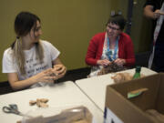 Volunteer Deanna Harper, left, creates plastic yarn balls, or plarns, and chats with librarian Jamie Bair, who crochets a plastic sleeping mat Tuesday evening at the downtown Vancouver Community Library. Kicking off the summer’s Make a Better World series, this event helped prepare the plastic yarn balls that will be crocheted into sleeping mats for homeless people.