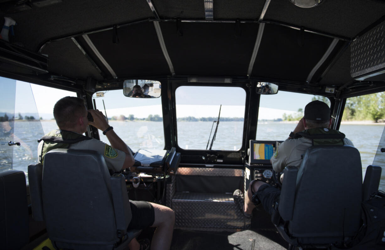 Clark County sheriff’s deputies Brett Anderson, left, and Todd Baker, right, use binoculars to check for up-to-date tags on jet skis while patrolling the Columbia River. Clark County marine deputies will be joining Portland area law enforcement in an emphasis this weekend focused on finding those choosing to drink and boat.