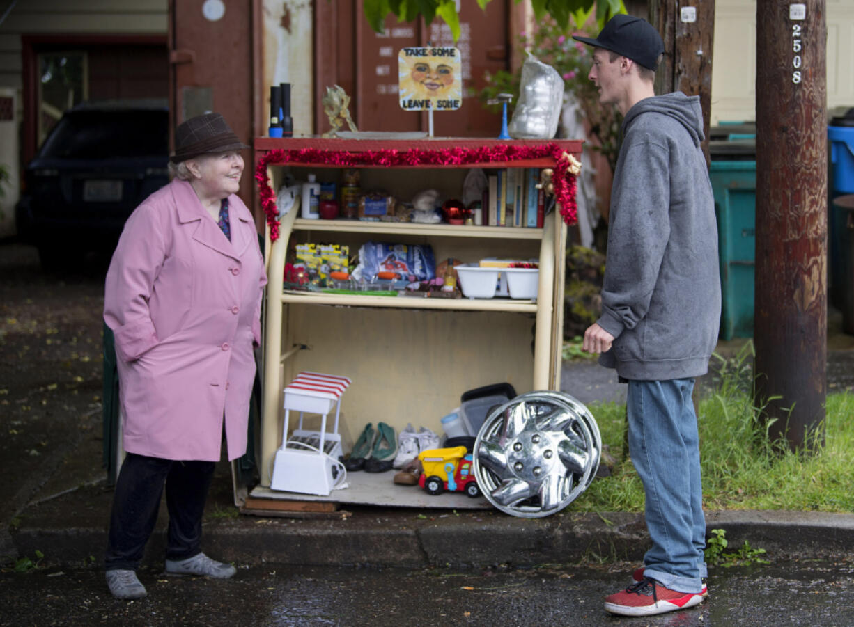 Tricia LaRose, left, chats with fellow Vancouver resident Zachery Bair on Thursday as he stops by her stand of free items.