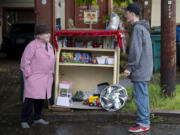 Tricia LaRose, left, chats with fellow Vancouver resident Zachery Bair on Thursday as he stops by her stand of free items.