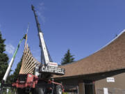 A crane holds a cross over the roof of First Congregational United Church of Christ in Hazel Dell while workers in a construction basket secure it into place.