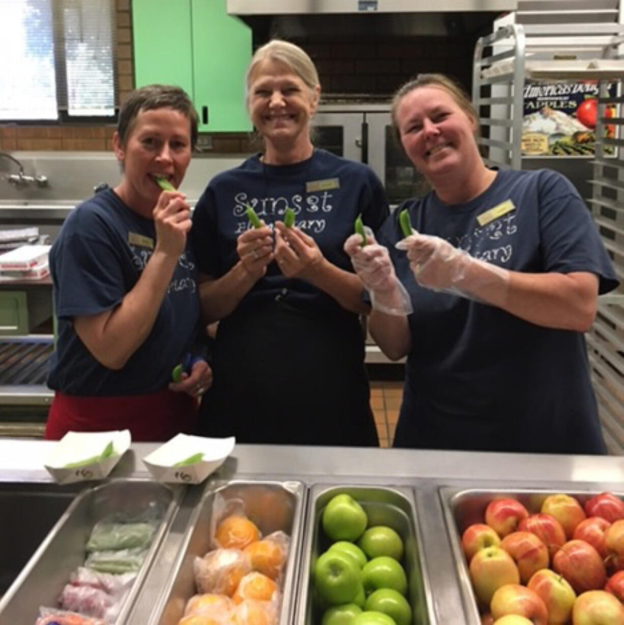 Five Corners: Sunset Elementary School food service staffers, from left, Shana Hysmith, Debbie Phares and Terri Lutz holding up snap peas, this month’s featured food through Washington State University Extension’s Supplemental Nutrition Assistance Program Education’s Harvest of the Month campaign.