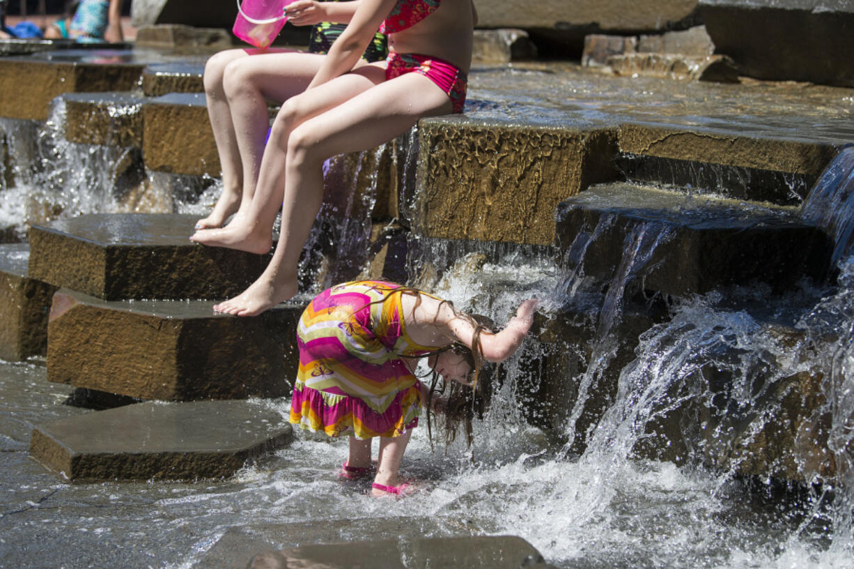 Jaslynn Johnson, 4, of Vancouver cools off while joining family members and kids of all ages in the fountain at Esther Short Park recently. At top, bare feet and rolled-up jeans were in style as visitors cooled off at the park. Residents will be looking for relief from the heat this week as high temperatures are expected.