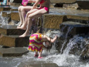 Jaslynn Johnson, 4, of Vancouver cools off while joining family members and kids of all ages in the fountain at Esther Short Park recently. At top, bare feet and rolled-up jeans were in style as visitors cooled off at the park. Residents will be looking for relief from the heat this week as high temperatures are expected.