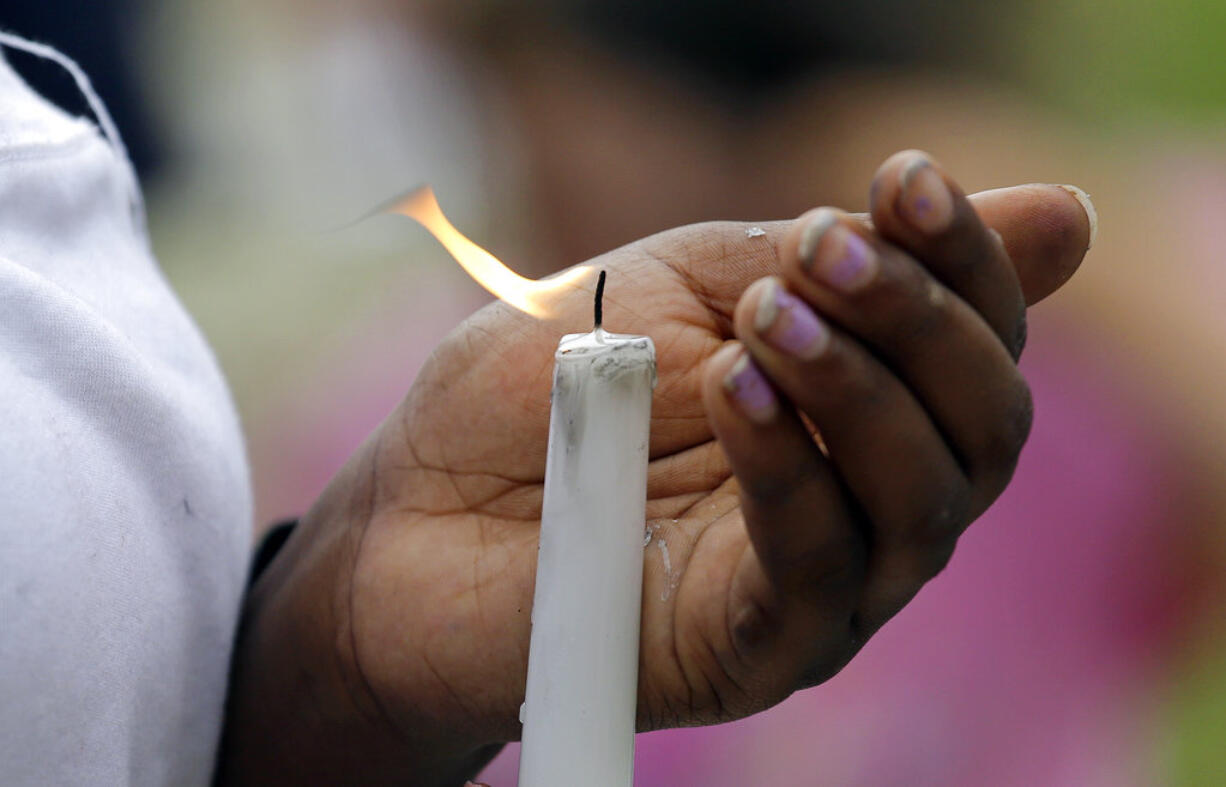 A teenager holds a candle against a breeze at a memorial outside where a pregnant mother was shot and killed at her apartment a day earlier by police Monday, June 19, 2017, in Seattle.