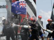 The crew of Emirates Team New Zealand spray champagne as they celebrate after defeating Oracle Team USA to win the America's Cup sailing competition Monday, June 26, 2017, in Hamilton, Bermuda.