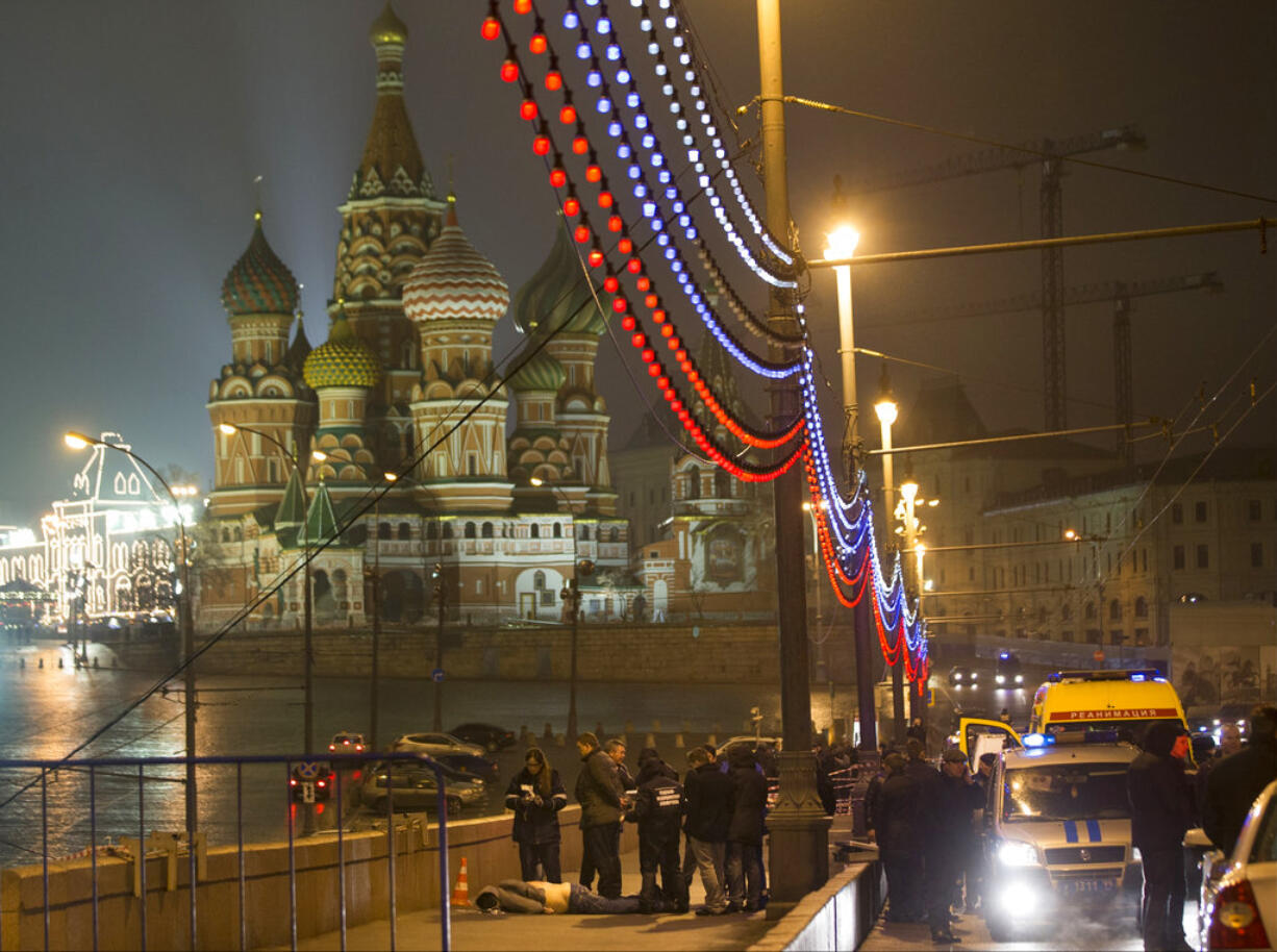 FILE - In this Saturday, Feb. 28, 2015 file photo Russian police investigate the lifeless body of Boris Nemtsov, a former Russian deputy prime minister and opposition leader just off Red Square, with St. Basil Cathidral in the background, in Moscow, Russia. A  jury on Thursday June 29, 2017 have found five men guilty in the assassination of Russian opposition leader Boris Nemtsov. Nemtsov, a top opponent of President Vladimir Putin, was shot in 2015 as he was walking across a bridge just outside the Kremlin.