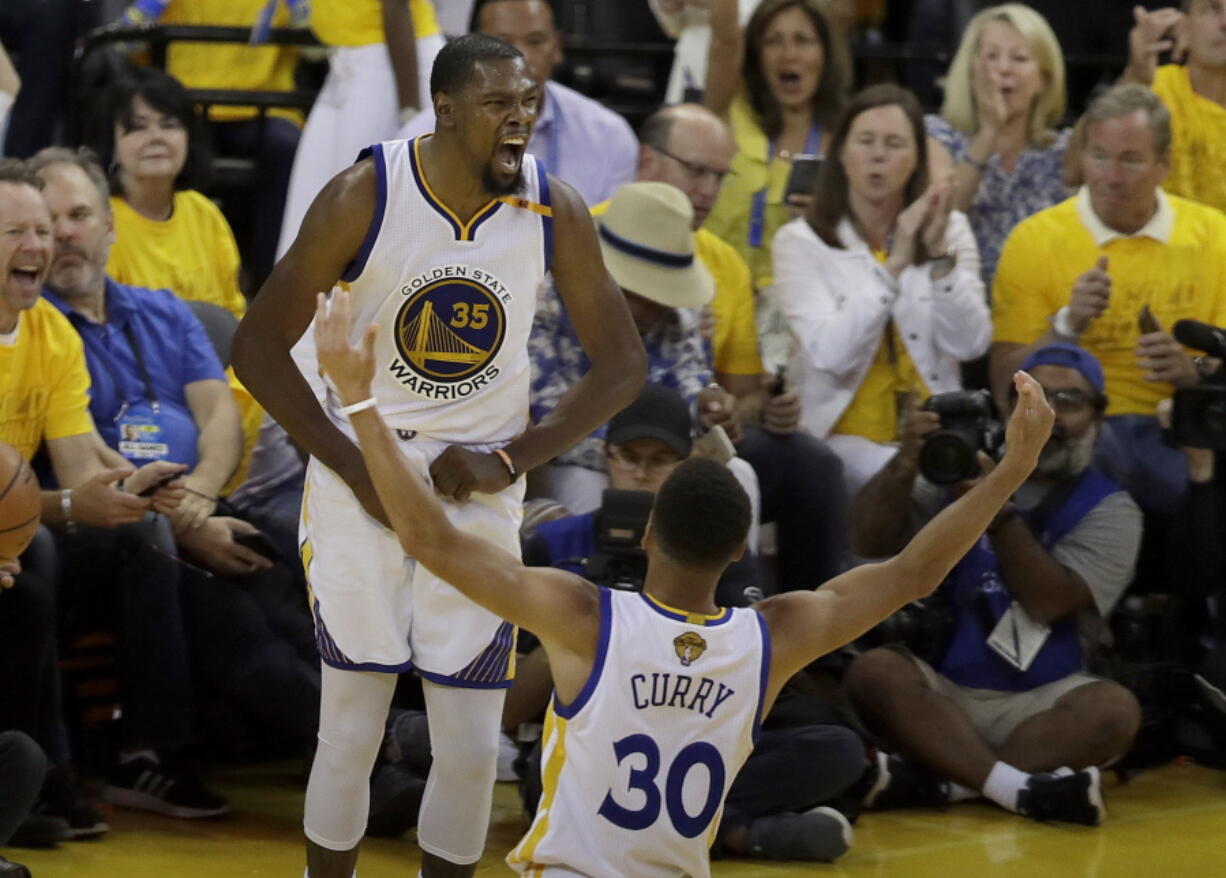 Golden State Warriors forward Kevin Durant (35) celebrates with guard Stephen Curry (30) Game 2 of the NBA Finals on Sunday. Curry had 32 points, 11 assists and 10 rebounds, while Durant contributed 33 points, 13 rebounds and six assists.