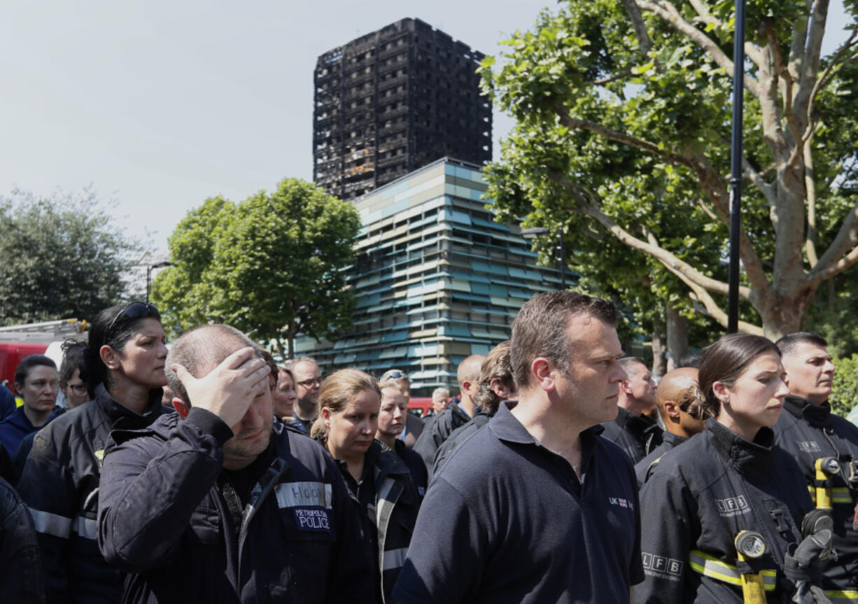 Emergency services workers take part in a minute’s silence in front of Grenfell Tower in London on Monday.