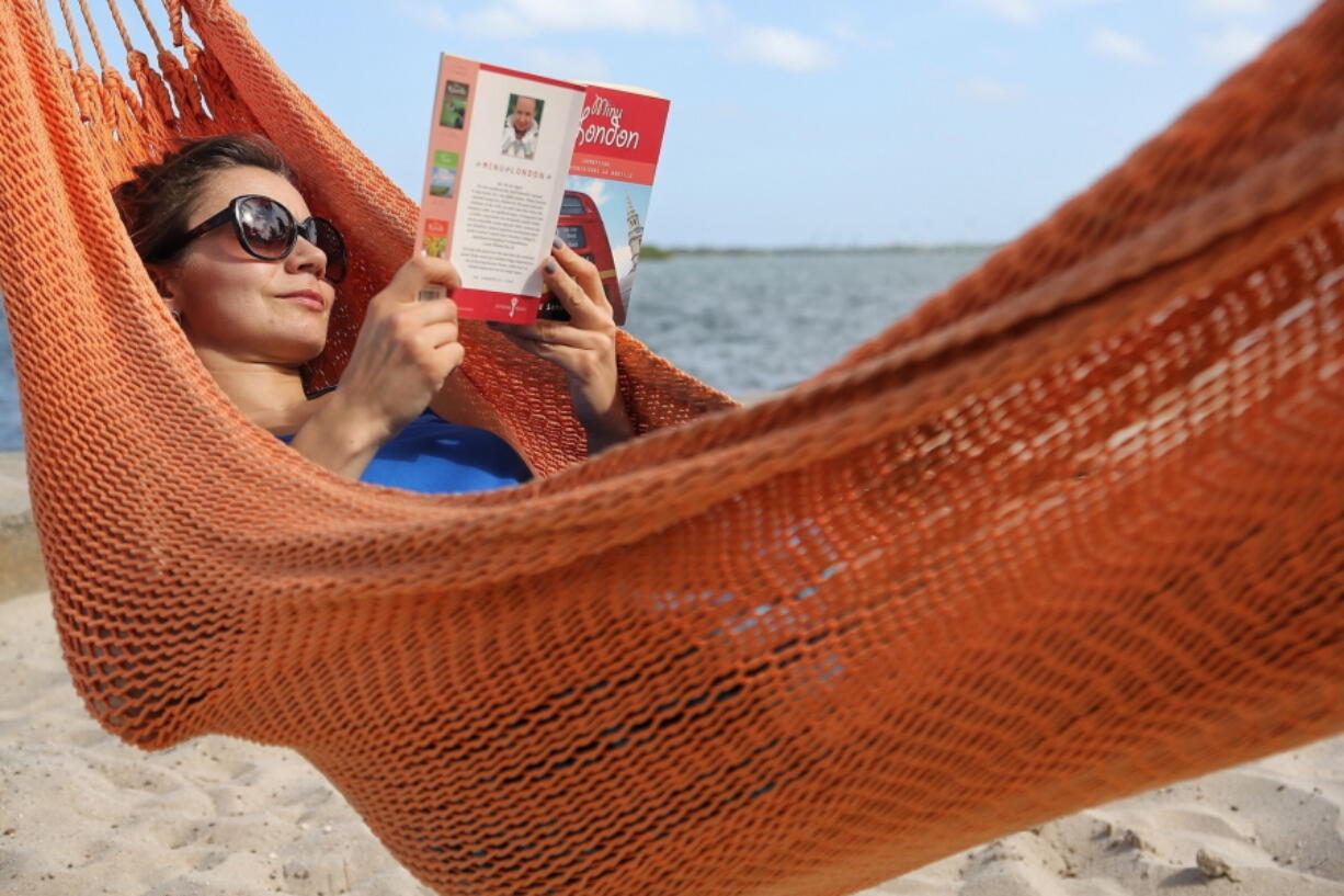 FILE - In this May 2, 2017, file photo, Kristiina Nurk, 34, enjoys a good book underneath the blue summer-like skies and weather as she vacations in Miami for a second day while on holiday. A new survey from The Associated Press-NORC Center for Public Affairs Research found that resting and relaxing is very or extremely important to three-fourths of Americans while on vacation.