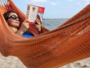 FILE - In this May 2, 2017, file photo, Kristiina Nurk, 34, enjoys a good book underneath the blue summer-like skies and weather as she vacations in Miami for a second day while on holiday. A new survey from The Associated Press-NORC Center for Public Affairs Research found that resting and relaxing is very or extremely important to three-fourths of Americans while on vacation.