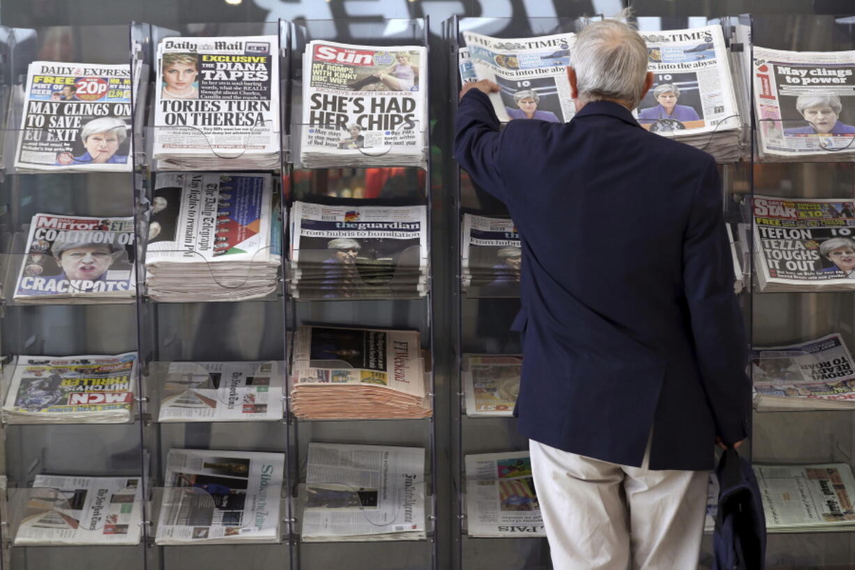 A man picks up a newspaper reporting on developments following Britain’s general election Saturday at a shop in London.