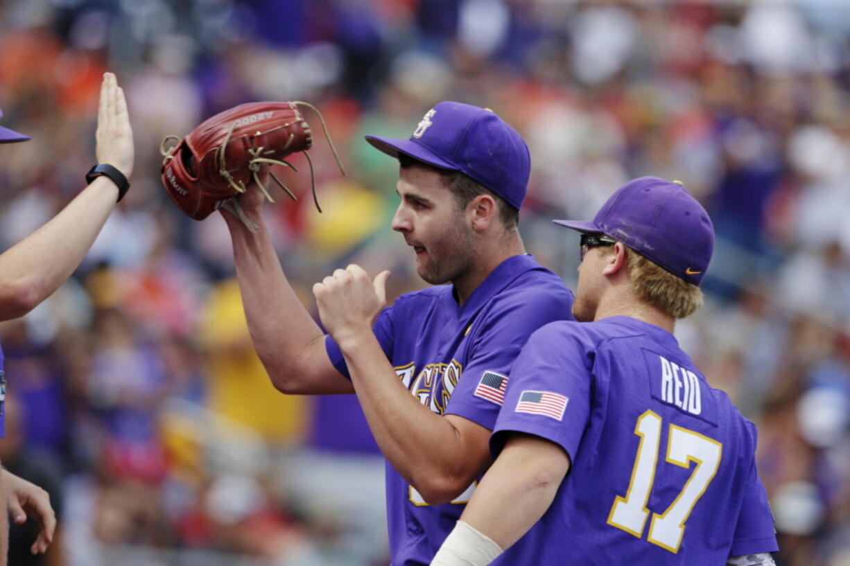 LSU pitcher Alex Lange celebrates with teammates as he leaves during the eighth inning of an NCAA College World Series baseball game against Oregon in Omaha, Neb., Friday, June 23, 2017.