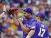 LSU pitcher Alex Lange celebrates with teammates as he leaves during the eighth inning of an NCAA College World Series baseball game against Oregon in Omaha, Neb., Friday, June 23, 2017.