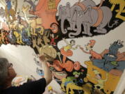 John Simpson, project director of exhibitions for The Amazing World of Dr. Seuss Museum, paints a mural based on artwork in the Dr. Seuss book “Did I Ever Tell You How Lucky You Are?” on a wall at the museum, in Springfield, Mass.