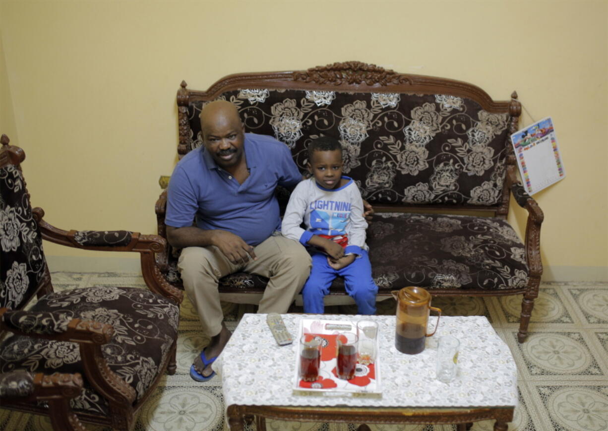 Sudanese activist Tayeb Ibrahim, who had worked to expose Sudanese abuses in the volatile South Kordofan province and hopes to see family living in Iowa, watches television with his son, Mohammed, on Wednesday in Cairo, Egypt. Dozens of Sudanese activists living in Egypt as refugees, who were close to approval for resettlement in the United States, now face legal limbo in Egypt.