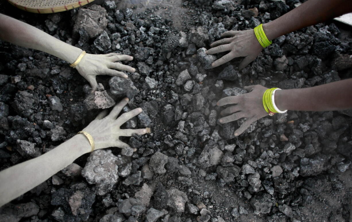 Indian women pick reusable pieces from heaps of used coal discarded by a carbon factory in Gauhati, India.