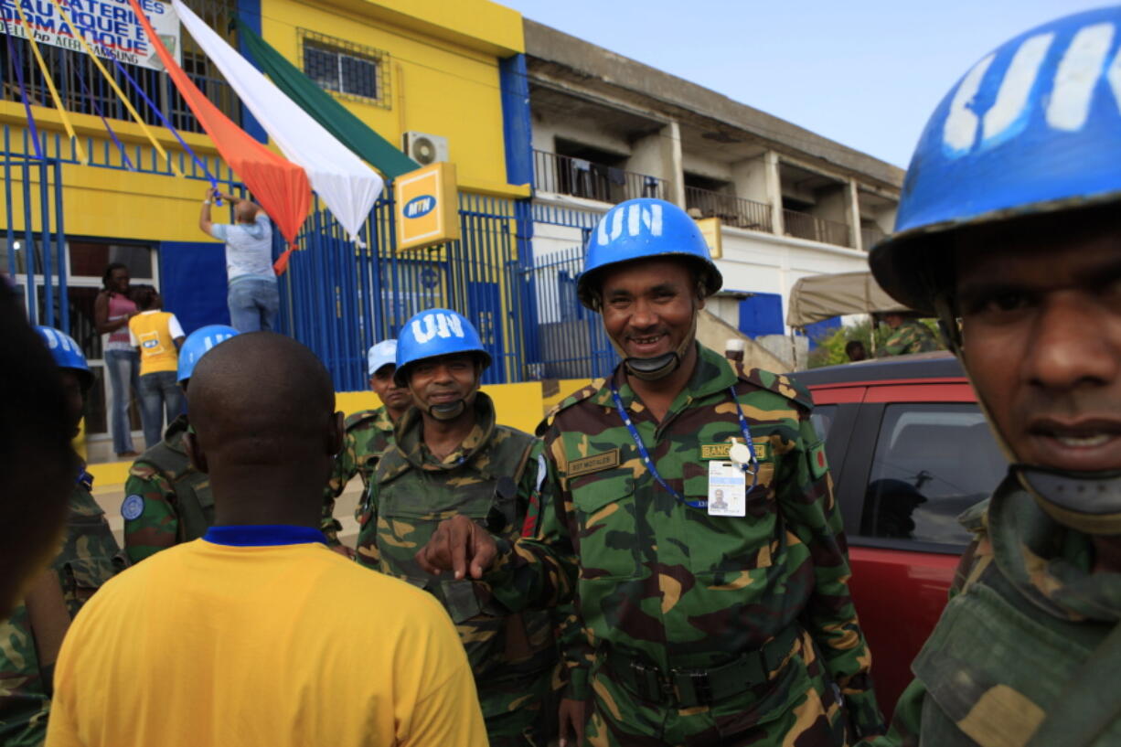 Bangladeshi United Nations soldiers stop to buy phone credit from a street vendor on the eve of President Alassane Ouattara’s inauguration, in Yamoussoukro, Ivory Coast, The U.N.