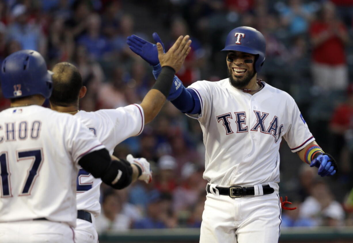 Texas Rangers' Shin-Soo Choo (17), of South Korea, and Rougned Odor, left rear, greet Robinson Chirinos, right, at the top of the dugout after Chirinos hit a solo home run off a pitch from Seattle Mariners' James Paxton in the fourth inning of a baseball game, Friday, June 16, 2017, in Arlington, Texas.