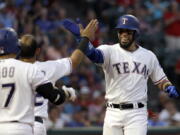 Texas Rangers' Shin-Soo Choo (17), of South Korea, and Rougned Odor, left rear, greet Robinson Chirinos, right, at the top of the dugout after Chirinos hit a solo home run off a pitch from Seattle Mariners' James Paxton in the fourth inning of a baseball game, Friday, June 16, 2017, in Arlington, Texas.