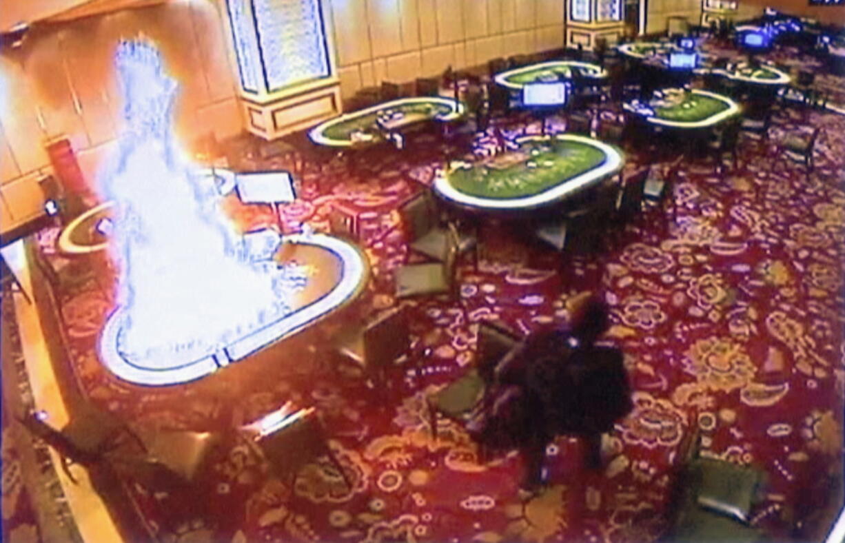 In this image made from security video released by Manila Police and Resorts World Manila on Saturday, June 3, 2017, a gunman walks away after setting fire to a gambling table in the Resorts World Manila entertainment and gambling complex in suburban Pasay city, southeast of Manila, Philippines on Friday, June 2, 2017. Dozens were killed during the attack, mostly from smoke inhalation.