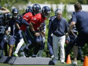 Seattle Seahawks head coach Pete Carroll looks on as Seattle Seahawks quarterback Russell Wilson, center, takes part in a drill during practice, Friday in Renton. Ted S.