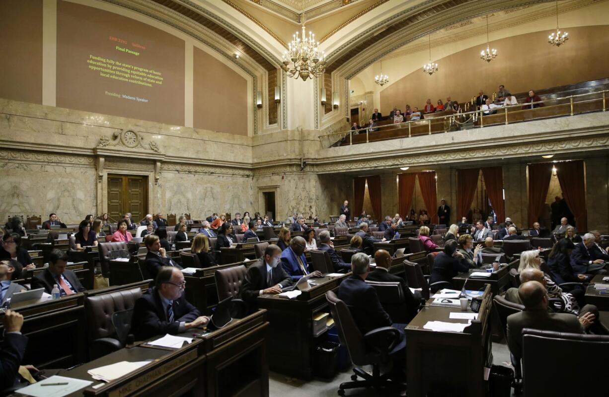 Representatives work on the House floor Friday during discussion of a bill to fully fund education in Washington at the Capitol in Olympia. Details of a new two-year state operating budget were released Friday, the same day Washington lawmakers must vote on the plan in order to prevent a partial government shutdown. (AP Photo/Ted S.