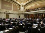 Representatives work on the House floor Friday during discussion of a bill to fully fund education in Washington at the Capitol in Olympia. Details of a new two-year state operating budget were released Friday, the same day Washington lawmakers must vote on the plan in order to prevent a partial government shutdown. (AP Photo/Ted S.