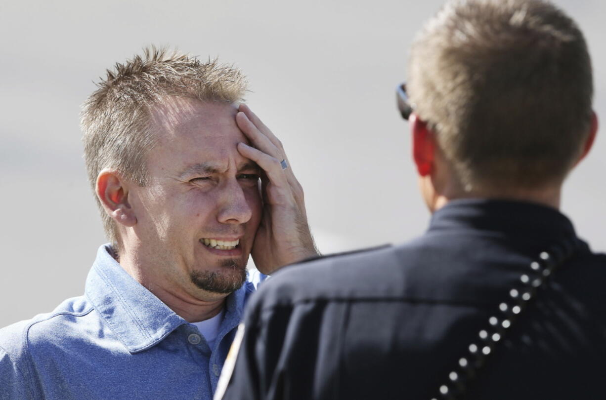 A man reacts as he talks to a Sandy police officer after a fatal shooting in the Salt Lake City suburb that left several people dead with another two injured on Tuesday in Sandy, Utah. The shooting in a middle-class neighborhood in Sandy was reported to police as a domestic dispute, said Police Sgt. Jason Nielsen.