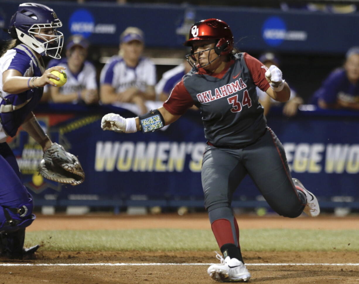 Oklahoma’s Fale Aviu avoids the tag of Washington’s Morganne Flores in the second inning of a Women’s College World Series in Oklahoma City, Friday.