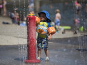 Carter Olsen, 2, of Vancouver plays in the water features at Klineline Pond in Salmon Creek on Monday afternoon. Temperatures are expected to reach near-record highs by midweek.