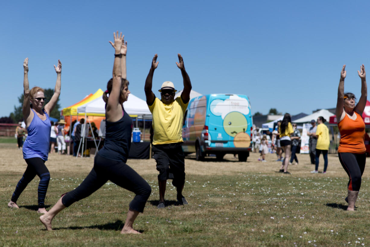 Yoga instructor, Mikeila Nienaber, in black, leads, from left, Elizabeth Merrill of Hockinson, Earl Ford of Vancouver, and Cherryl Burkey of Vancouver in a yoga demonstration at the Fourth Plain Multicultural Festival at Fort Vancouver High School. The event brought together organizations and businesses from the Fourth Plain corridor for an afternoon of festivities.