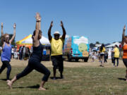 Yoga instructor, Mikeila Nienaber, in black, leads, from left, Elizabeth Merrill of Hockinson, Earl Ford of Vancouver, and Cherryl Burkey of Vancouver in a yoga demonstration at the Fourth Plain Multicultural Festival at Fort Vancouver High School. The event brought together organizations and businesses from the Fourth Plain corridor for an afternoon of festivities.